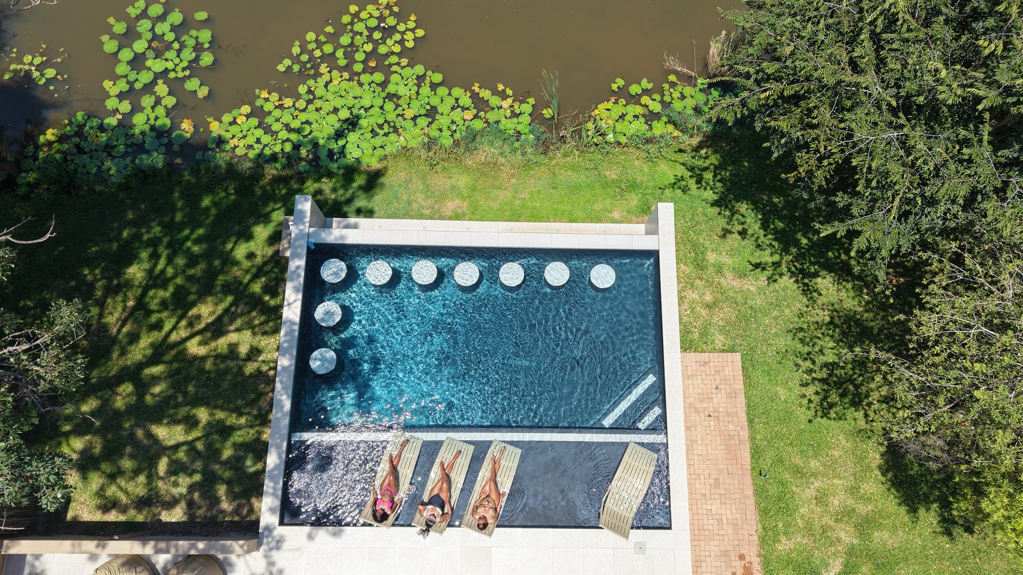 Aerial view of pool with guests, river and lily pads