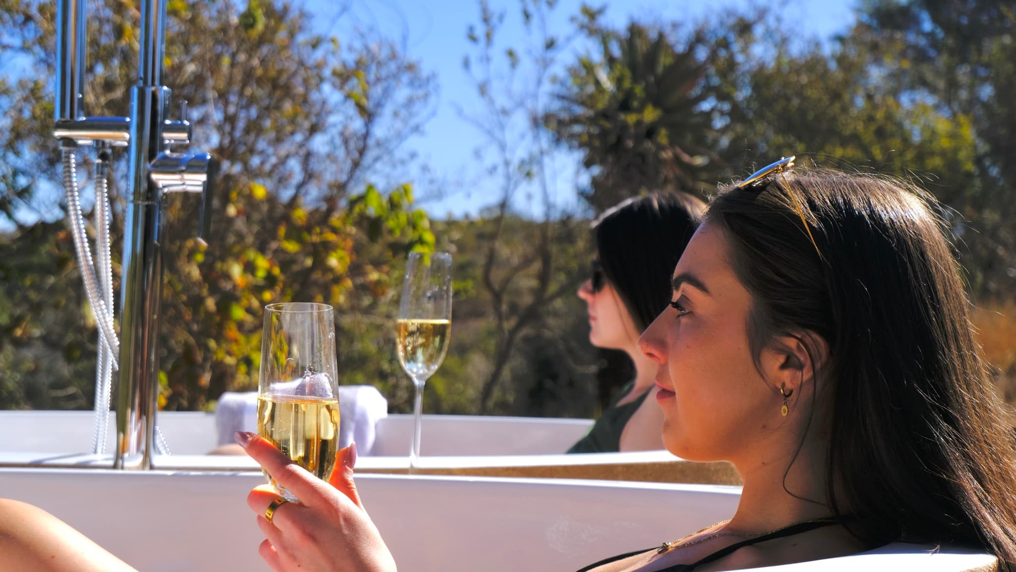 Two guests enjoying champagne in outdoor stone bathtubs